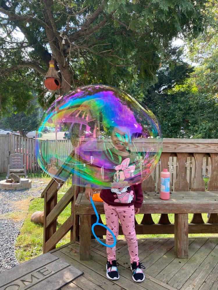 A child playing inside a giant soap bubble outdoors A child playing inside a giant soap bubble outdoors